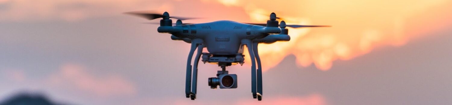 Drone with camera flying at sunset